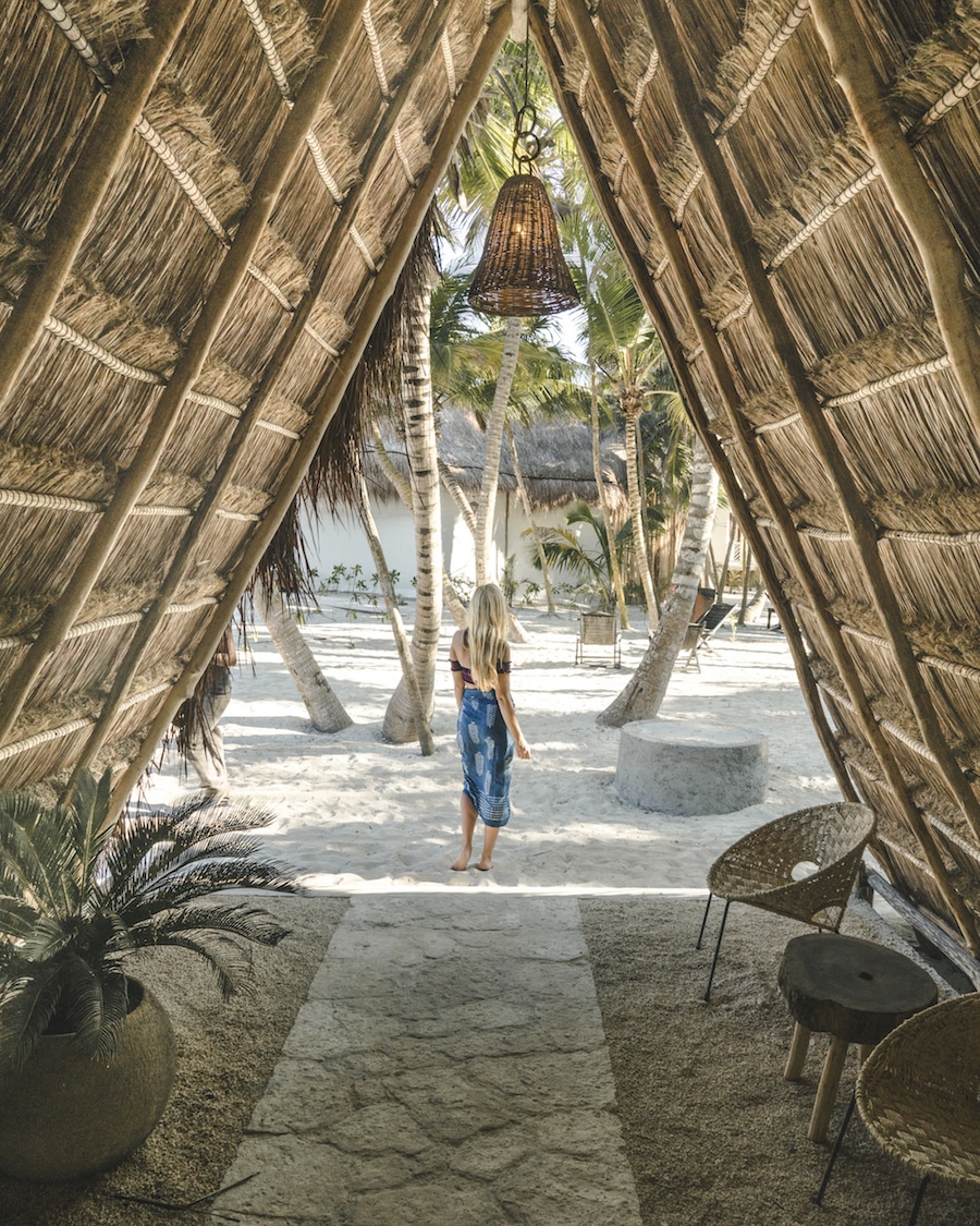 me outside small beach hut surrounded by palm trees standing on sand