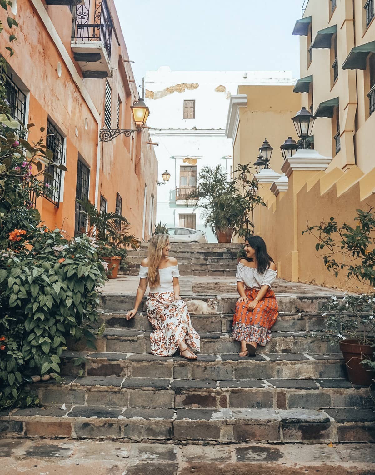 Friends sit on stairs surrounded by colorful buildings in Puerto Rico