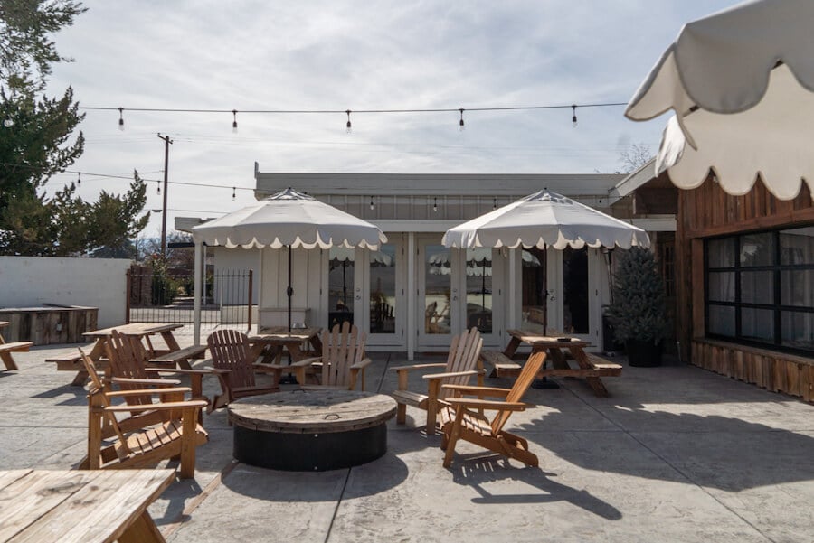 Outdoor patio with white umbrellas, wooden tables and string lights