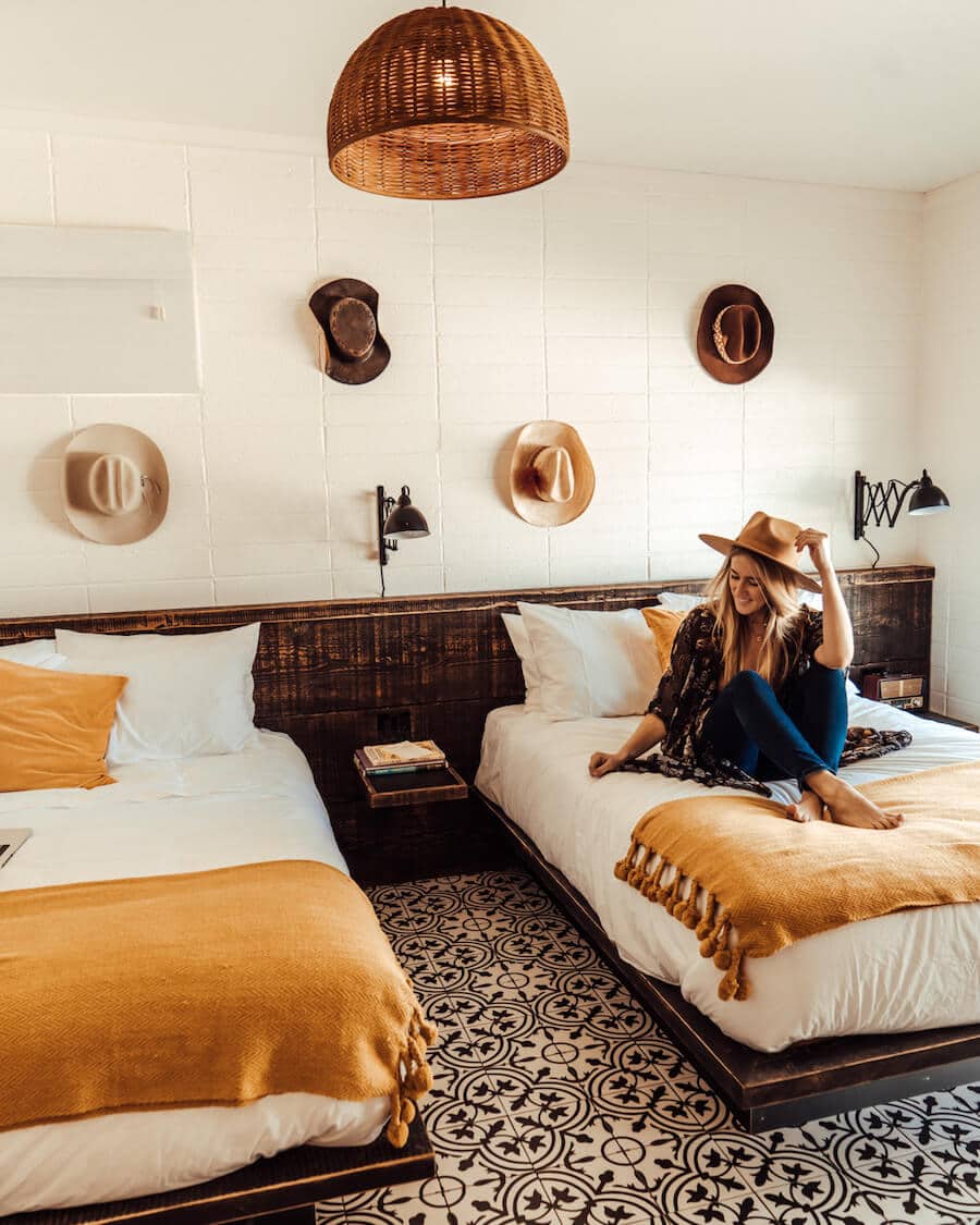 Interior of rooms at Cuyama Buckhorn with hats on the wall and girl sitting on bed