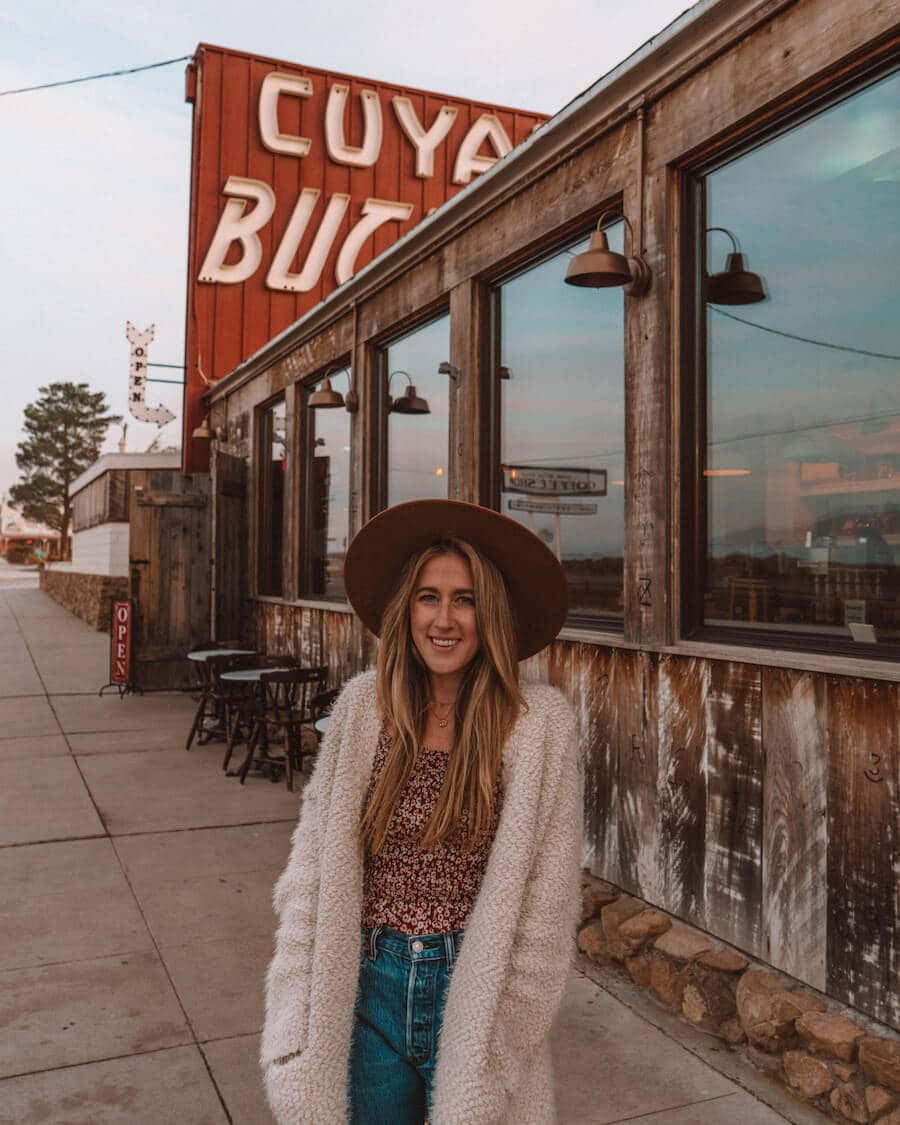 Exterior of the Cuyama Buckhorn with retro signage and girl standing in front with hat