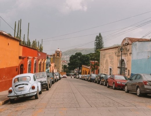 A colorful street in Oaxaca City with an old VW bug
