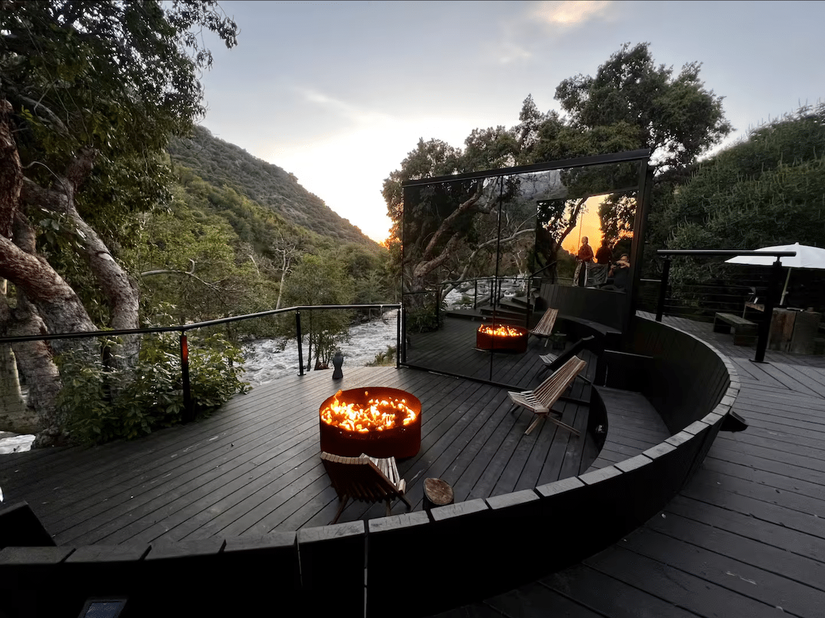 Mirrored home overlooking a river with a fire pit burning.