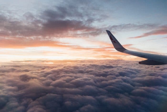 A plane wing in the clouds at sunset.