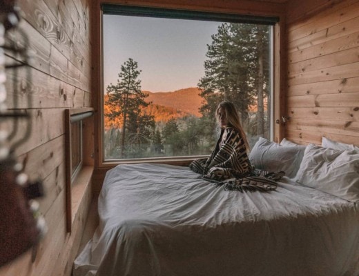 Girl sitting on bed in the Getaway House cabin in Big Bear