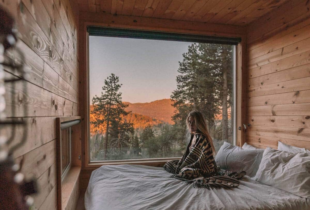 Girl sitting on bed in the Getaway House cabin in Big Bear