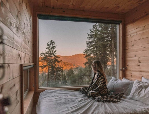 Girl sitting on bed in the Getaway House cabin in Big Bear