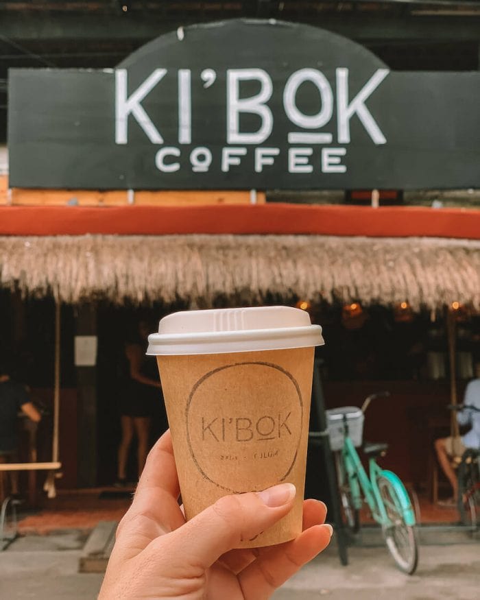 Small late being held up in front of Ki'Bok Coffee, Tulum