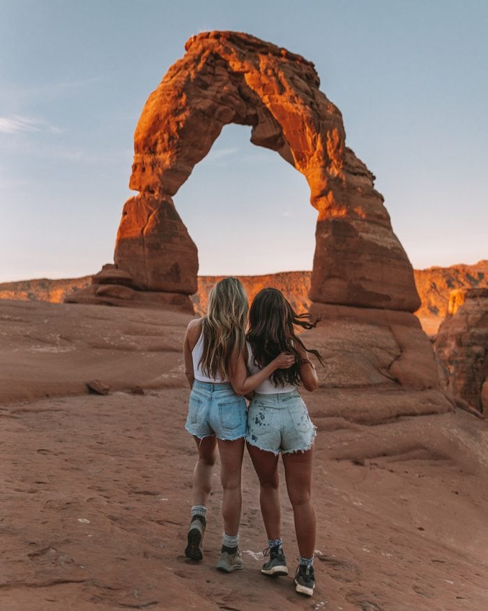 Two women in front of Delicate Arch in Arches National Park