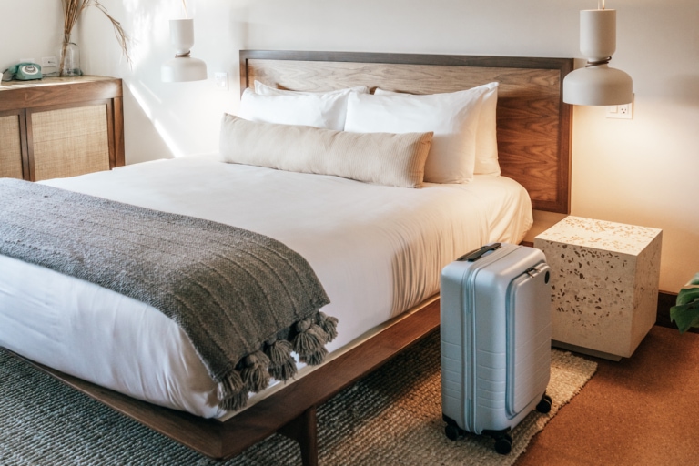 Monos luggage sitting next to a hotel bed
