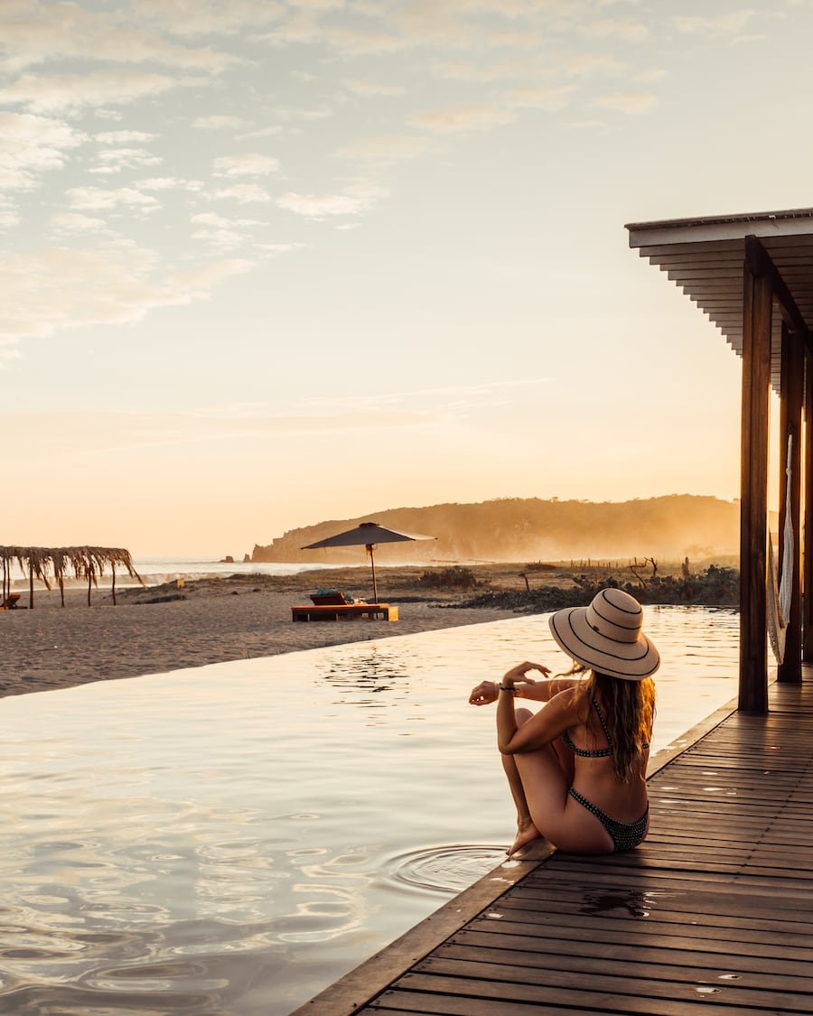 Michelle Halpern sitting near pool at sunset at Puerto Escondido Hotel posing for Mexico travel tips blog