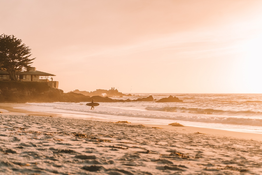 A surfer headed into the waves at sunset in Carmel, California