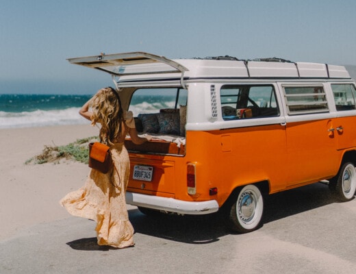 Michelle Halpern standing next to a vintage orange campervan by the beach