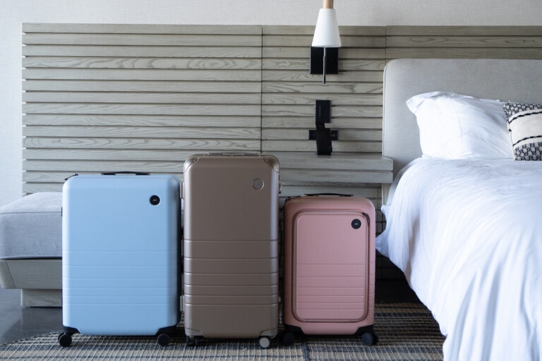 Three monos travel suitcases lined up in a hotel room next to each other