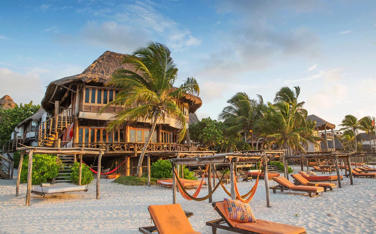 Exterior of Amansala hotel in Tulum with bright orange lounge chairs