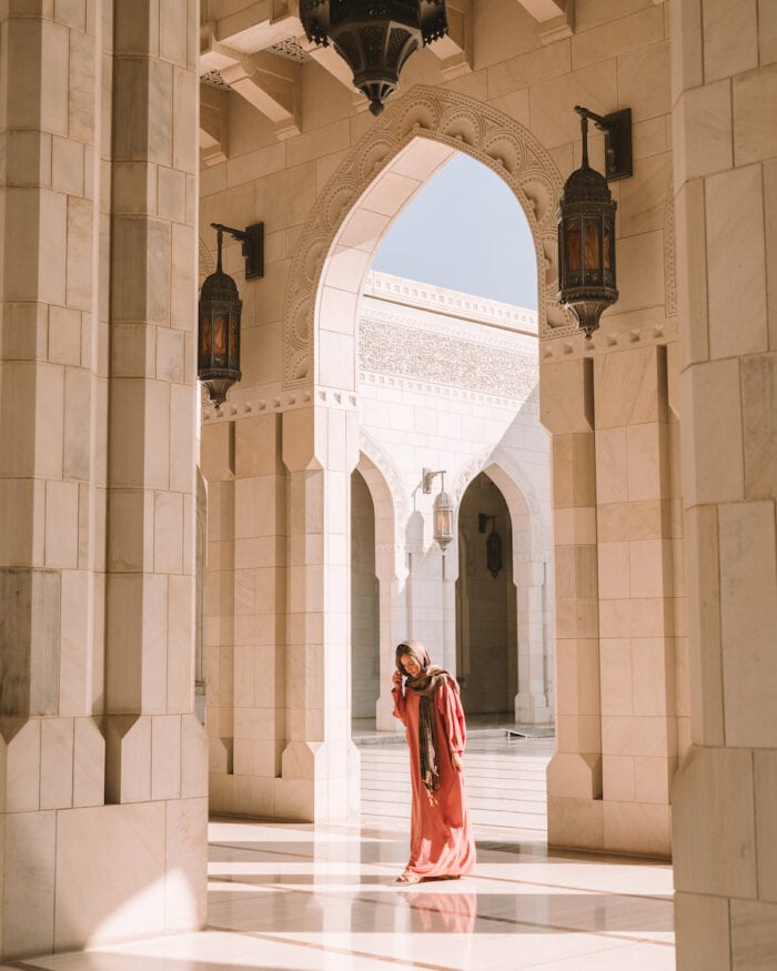 Michelle Halpern under the arches at the Sultan Qaboos Grand Mosque in Muscat -Oman road trip itinerary