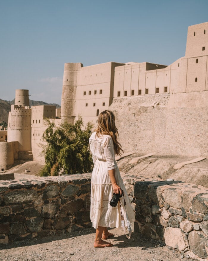 Michelle Halpern holding her camera in front of Oman's Bahla Fort