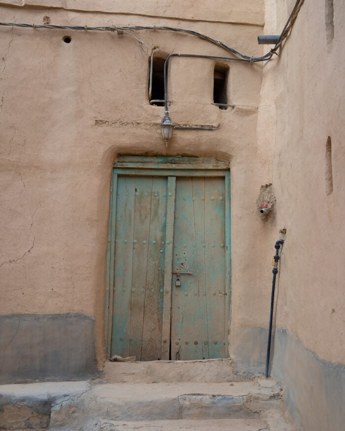 Beautiful turquoise door inside the Al Hamra Mud Village/ Oman road trip itinerary 