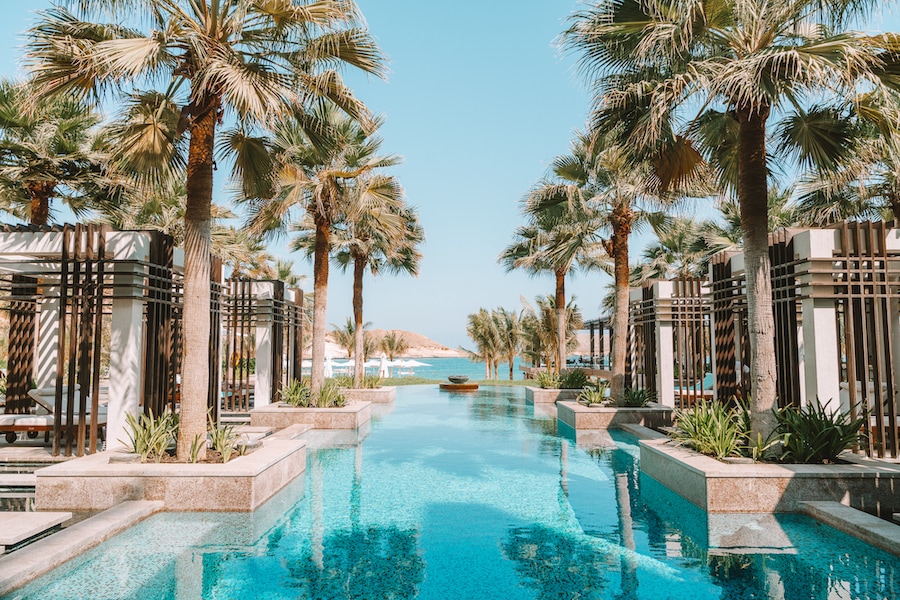 Pool at Jumeirah Muscat Bay surrounded by luxurious bungalows and palm trees