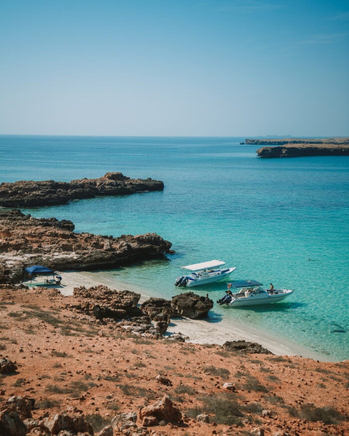 Boats anchored along the beach against turquoise blue waters in the Daymaniyat Islands