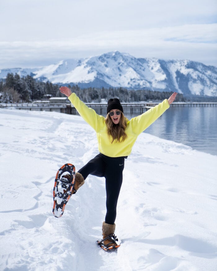 Michelle Halpern wearing a neon fleece and snowshoes in front of Lake Tahoe