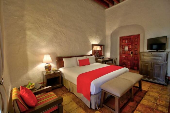 Bedroom with white and red linens at the Quinta Real Oaxaca