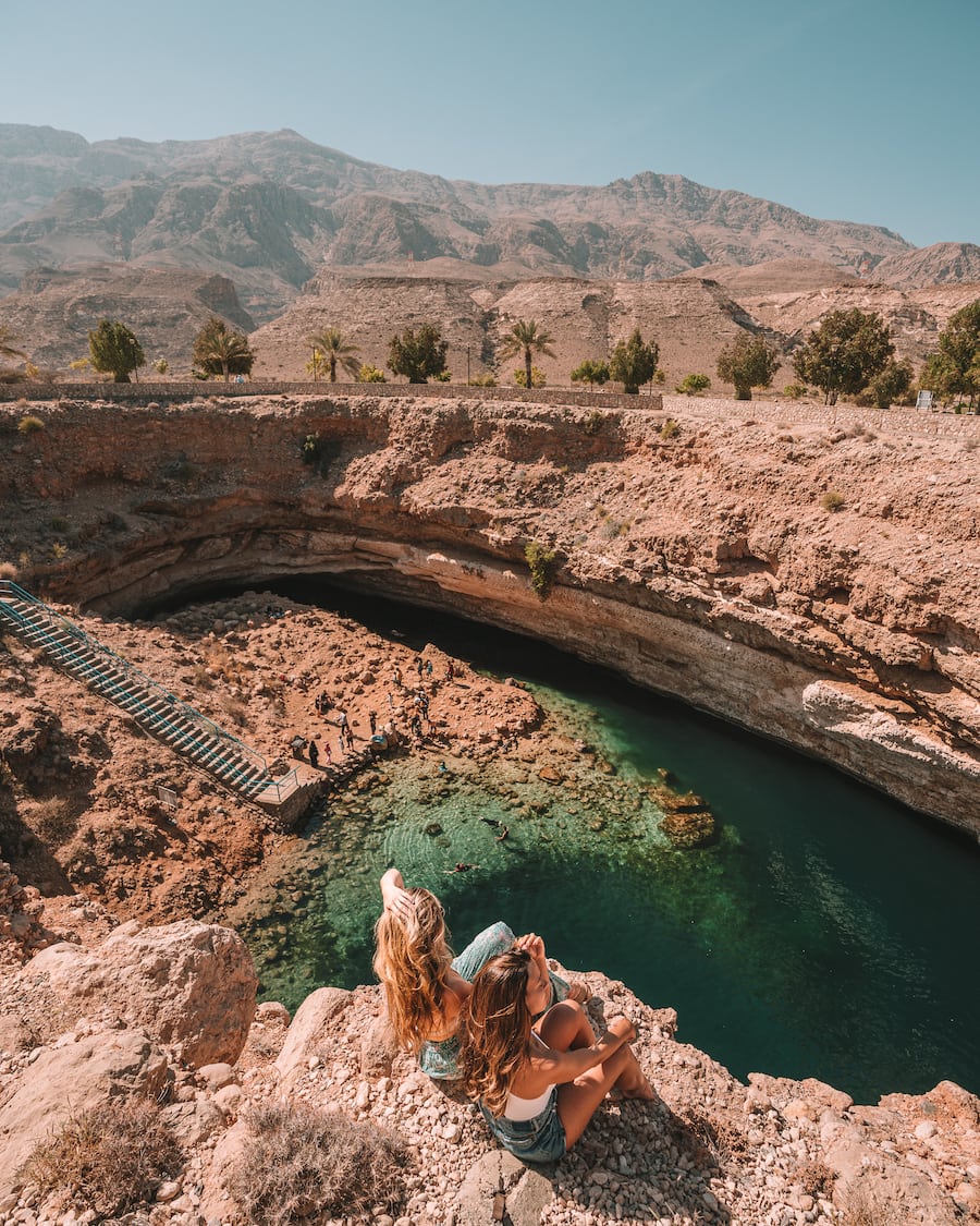 Michelle Halpern and Catarina Mello sitting at the edge of the Bimmah Sinkhole in Oman