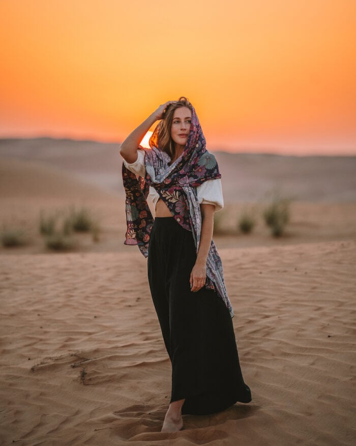 Packing List for International Travel Michelle Halpern standing in the Wahiba Sands desert at sunset