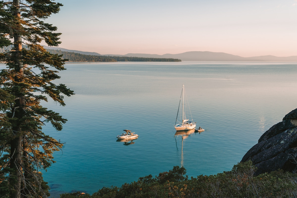 Glassy view of Lake Tahoe with a sailboat and motor boat in the distance