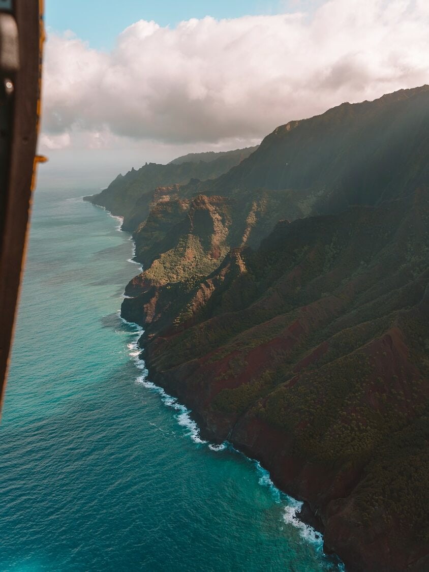 Aerial view down the Na Pali coast from inside a Kauai doors off helicopter tour