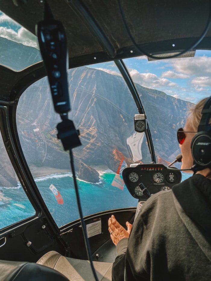 View inside the doors off helicopter of the pilot maneuvering towards the Na Pali coast