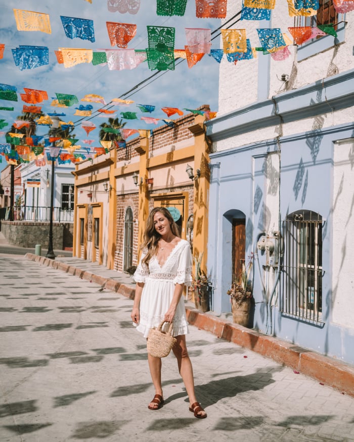Michelle Halpern standing in a white dress on the colorful streets of Todos Santos