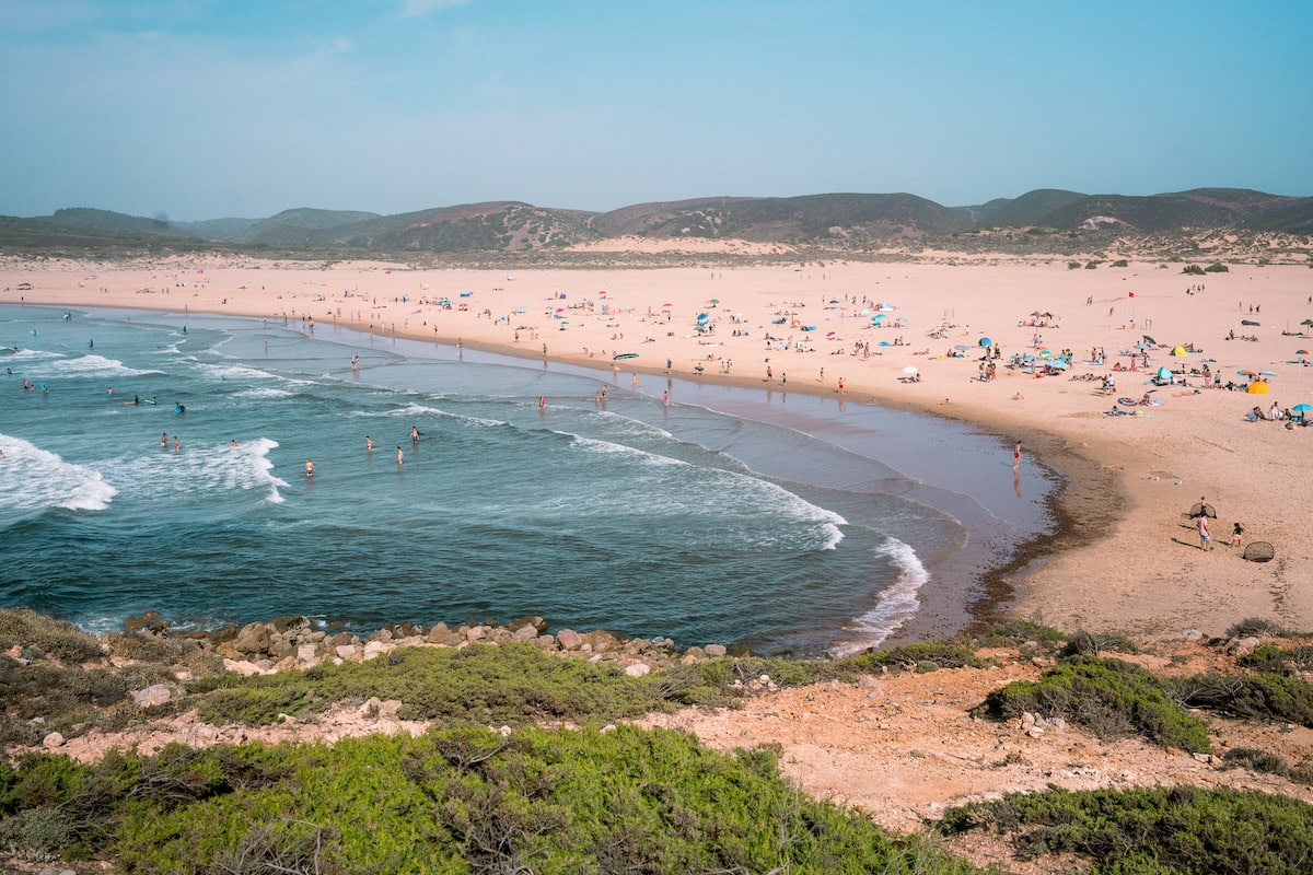 View of tons of swimmers and surfers at Bordeira Beach in West Algarve Portuga 