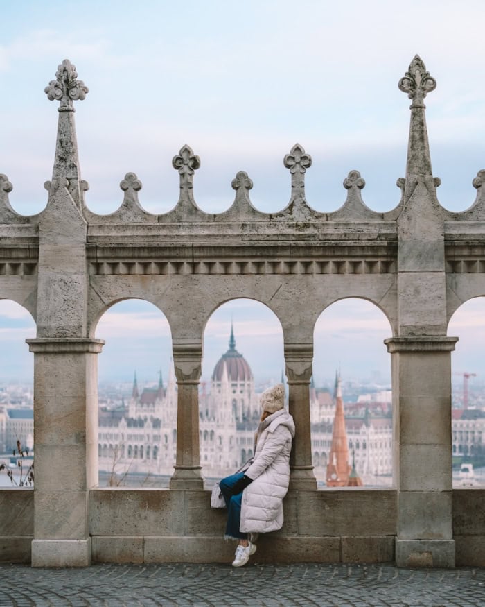 Michelle sitting at Fishermans Bastion Michelle sitting at Fishermans Bastion in Budapest wearing a large puffy white coat, mittens and hat.