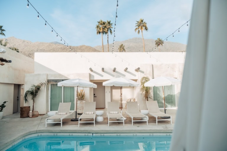 Pool and pool umbrellas with palm trees in background at Yara Hotel in Palm Springs