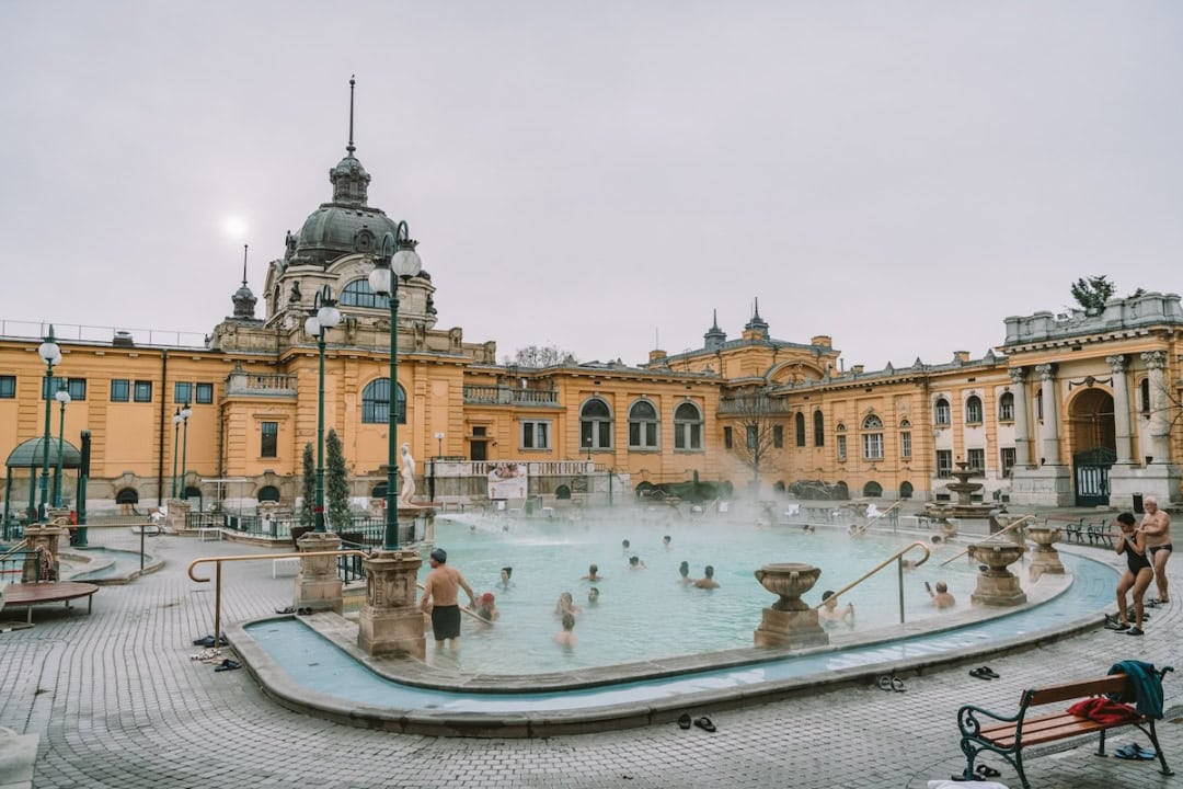 Széchenyi bath in Budapest with people lounging in the outdoors pools