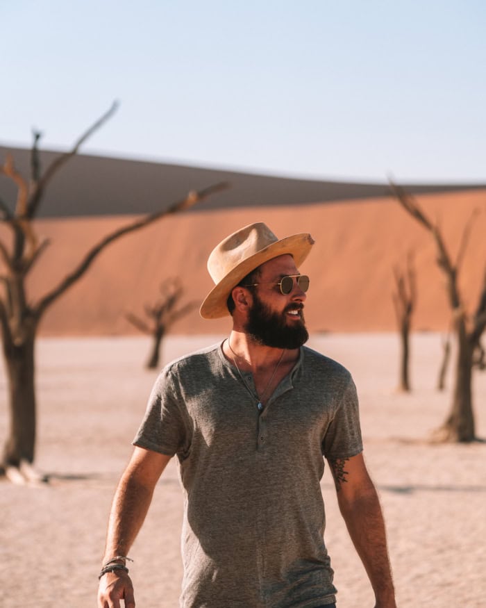 JT Deadvlei area JT wearing a hat exploring the Deadvlei area, with dead trees and sand dunes in the background.