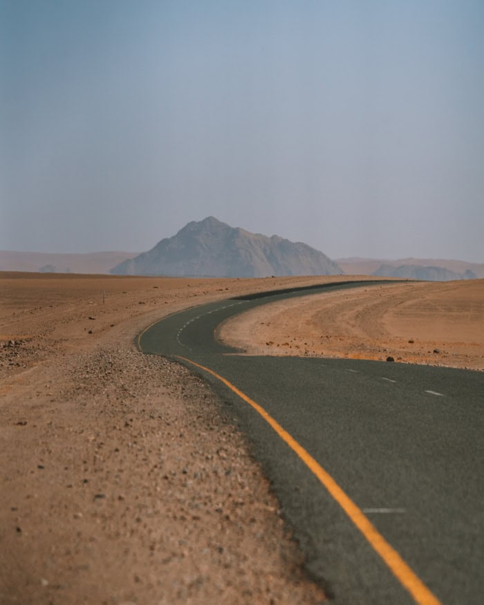 road Sossusvlei Lonely paved road stretching through Sossusvlei with small peak in the distance.