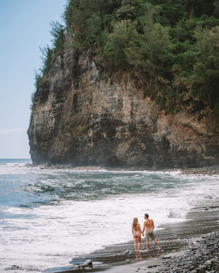 JT and Michelle beach JT and Michelle exploring the ocean on a black sand beach featuring cliffs on the coastline.