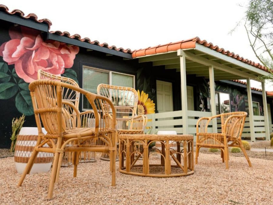 outdoor patio at Fleur Noire Image of an outdoor patio at Fleur Noire featuring wooden furniture and a floral wall in the background.