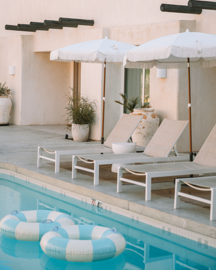 Image of the pool in the Yara hotel at Palm Springs. Featuring sun loungers, umbrellas and two pool floaties.