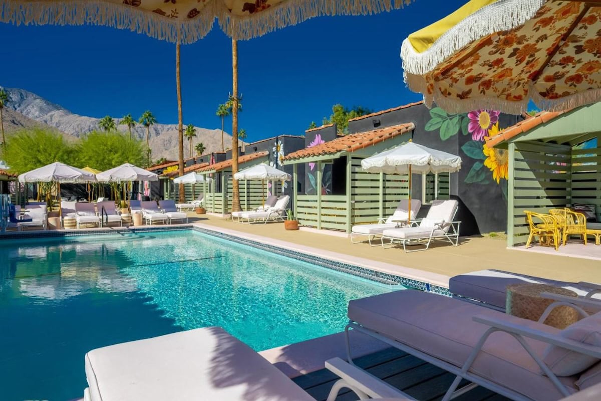 Fleure Noire in Palm Springs Image of the central pool at Fleure Noire in Palm Springs featuring a floral side wall and colorful umbrellas.