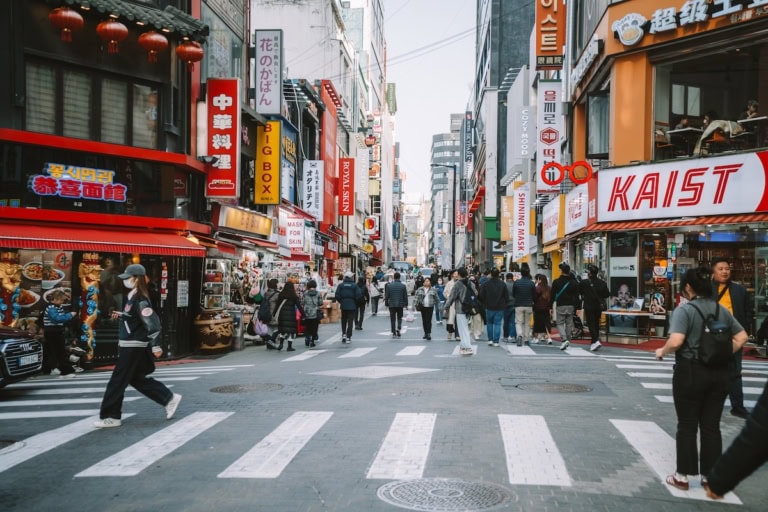 Busy street in Seoul, South Korea filled with street signs and shops and people
