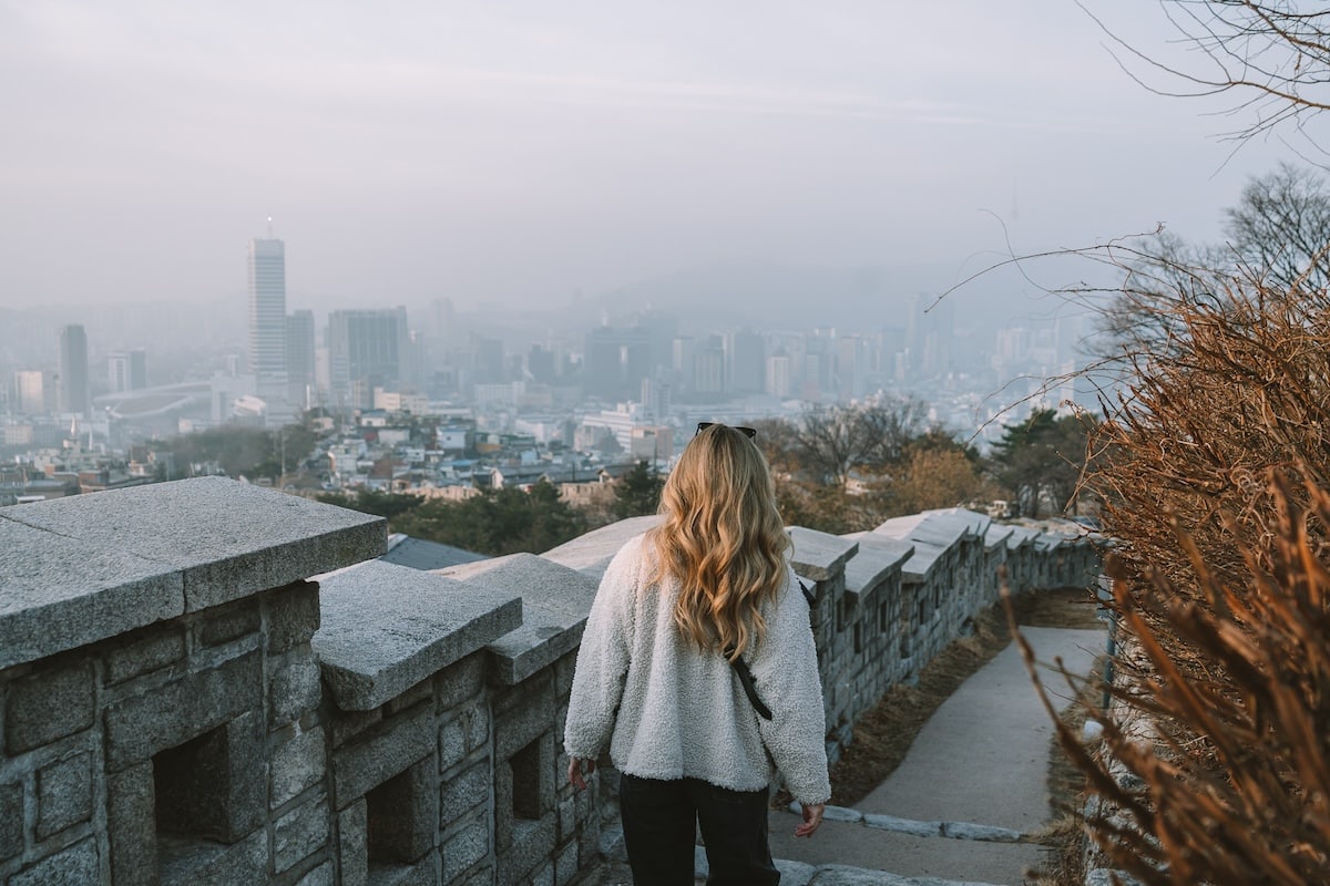 stone staircase Michelle Halpern walking along a path with a view that looks out over the skyline of Seoul