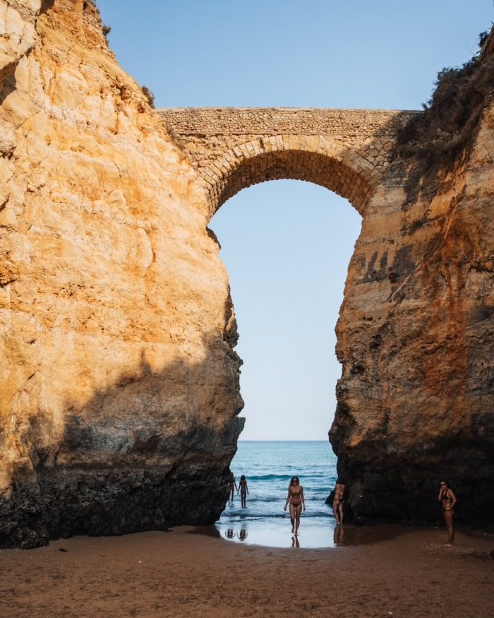 limestone cliffs on a beach Michelle Halpern stands under a stone archway flanked by two limestone cliffs on a beach.