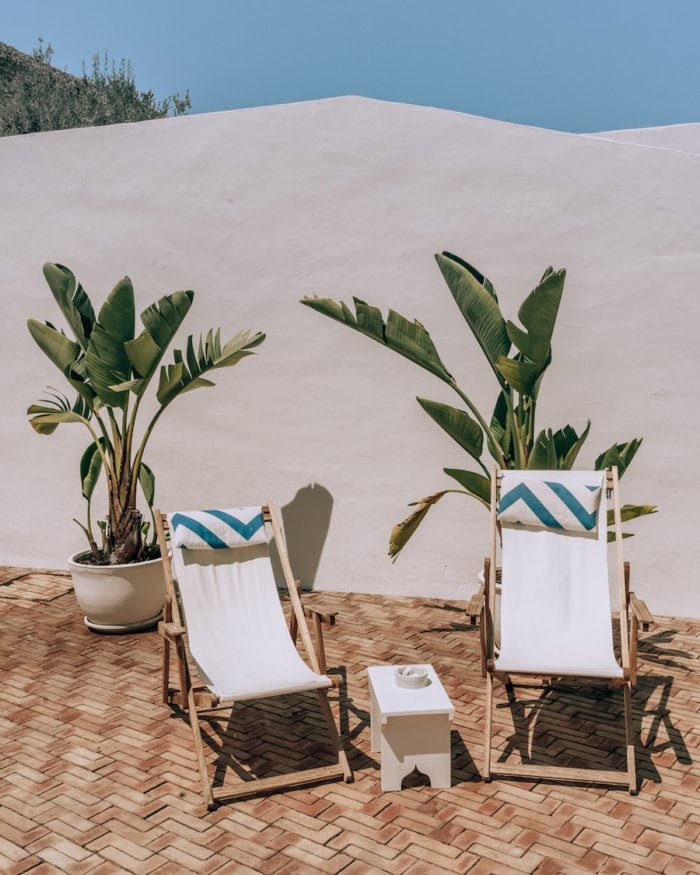 Casa Mae deck Two white lounge chairs with blue stripes on a sunny deck at Casa Mae