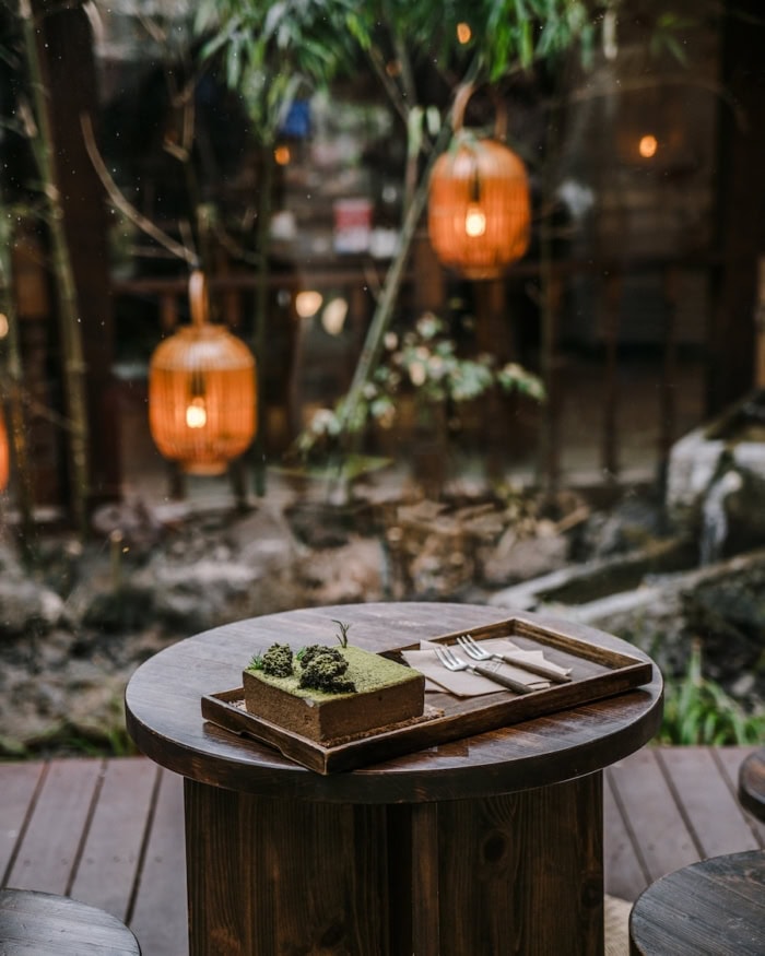 Cheongsudang Bakery cake Wooden table with lit lanterns in the background with a green cake on it.