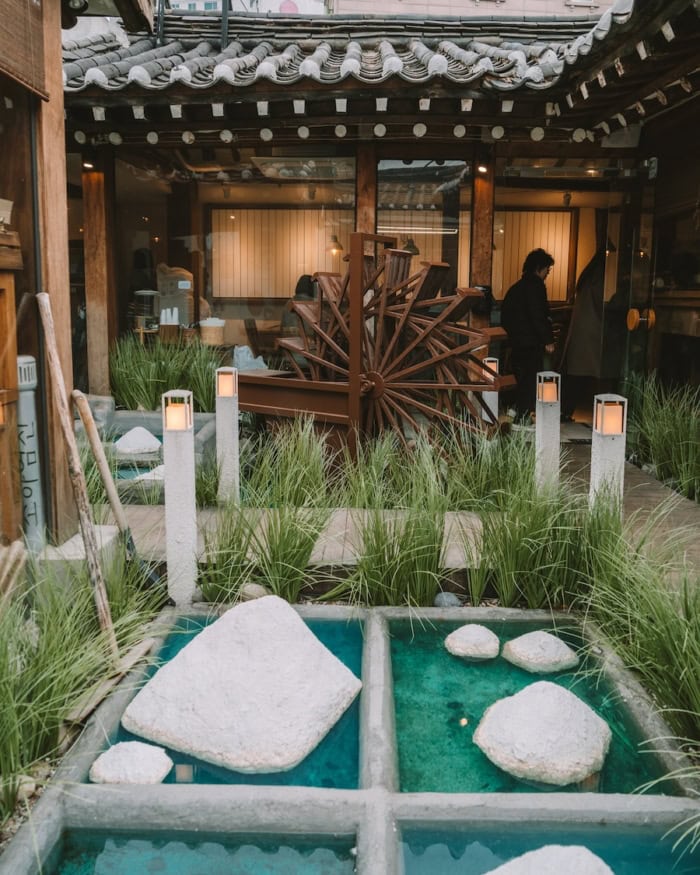 Exterior courtyard of Soha Salt Pond which features turquoise pools and fake salt mounds with a wheel in the background.