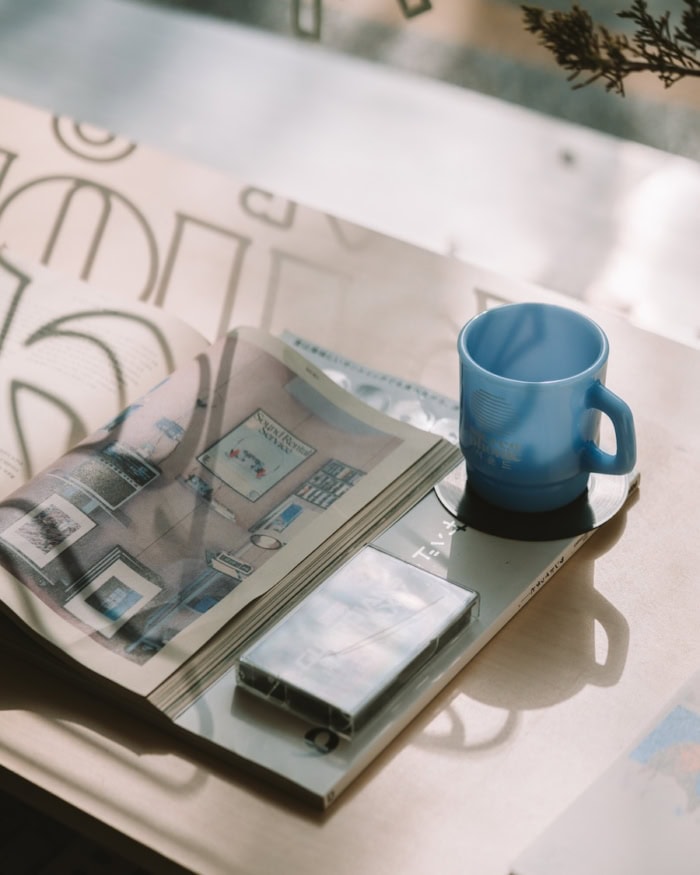 mug and magazine Display in window featuring a blue mug and magazine with the shadow from the letters in the window casting over it.
