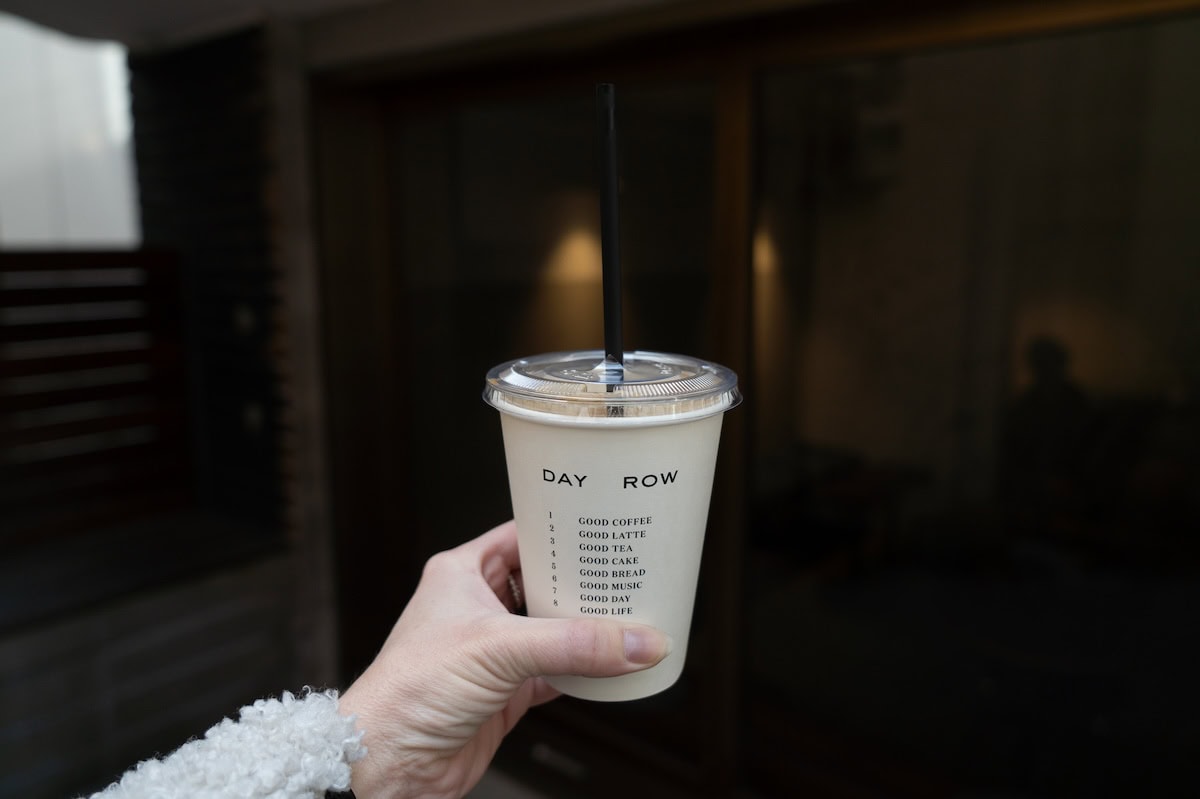 Day Row seoul Hand holding up white iced coffee cup that says "Day Row" on it